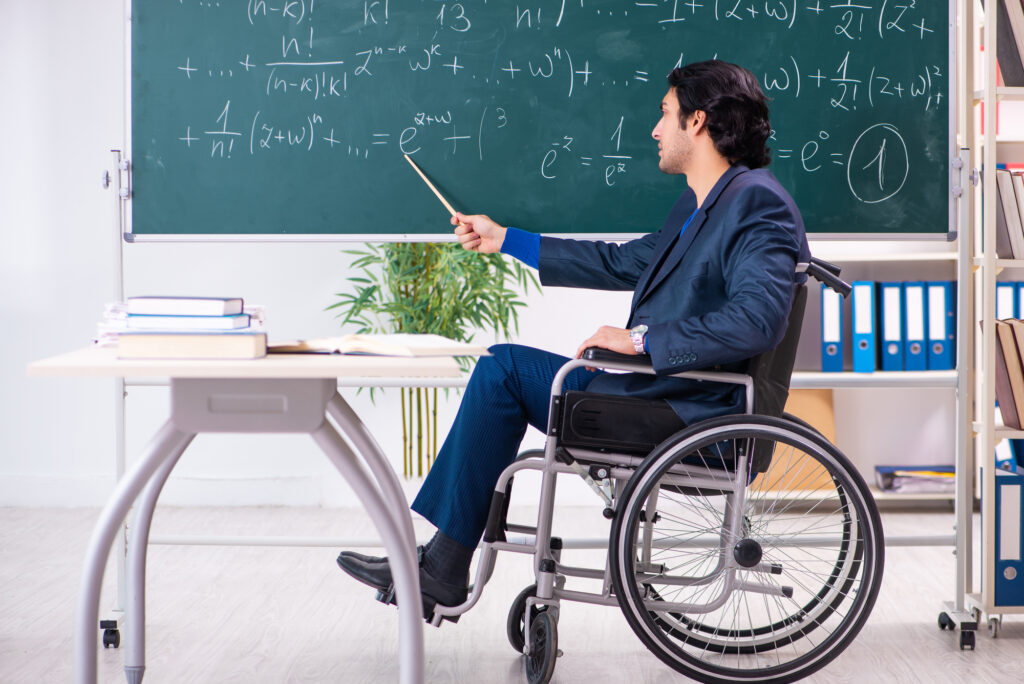 Young handsome man in wheelchair in front of chalkboard