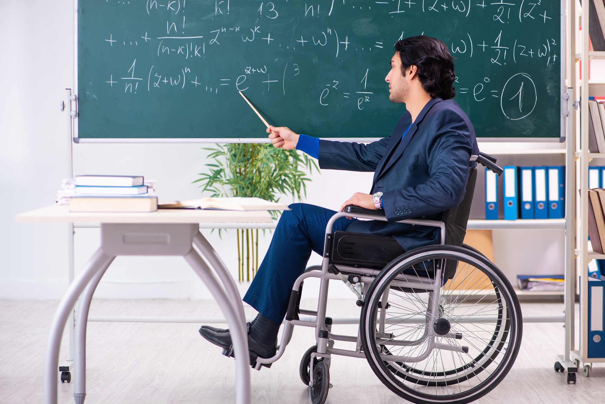 Young handsome man in wheelchair in front of chalkboard