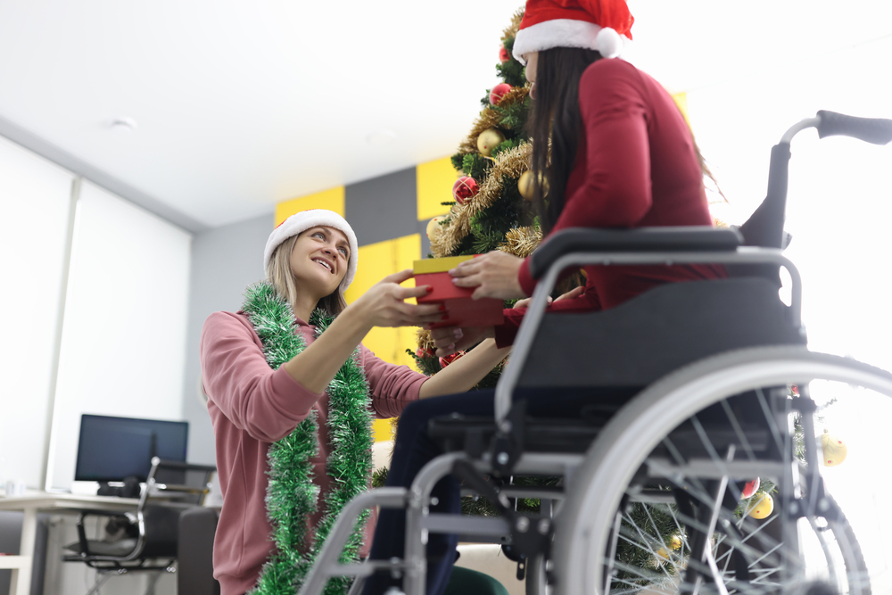 Woman gives New Year's gift to girl in wheelchair. Gifts for people with disabilities concept