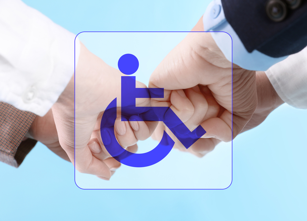 Three hands join together with a blue wheelchair symbol overlay, symbolizing unity and support for disability awareness against a light blue background.